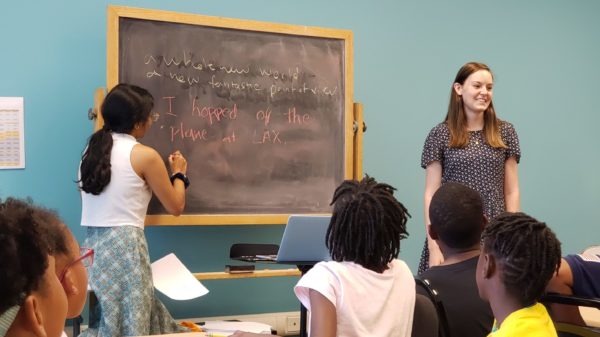 826DC interns stand in front of a chalkboard as students look on.