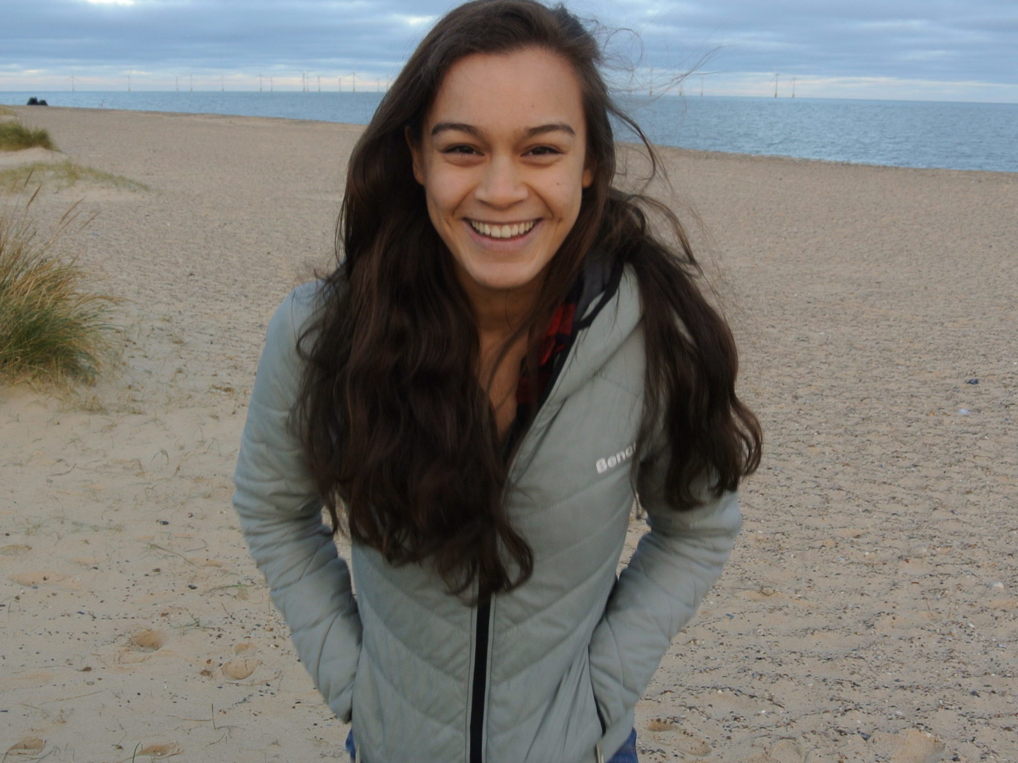Anja Kuipers, the 826DC Public Programs Coordinator, is laughing and wearing a gray jacket on the beach.