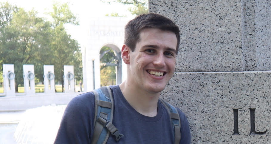 Nate Schwartz smiles in front of a monument