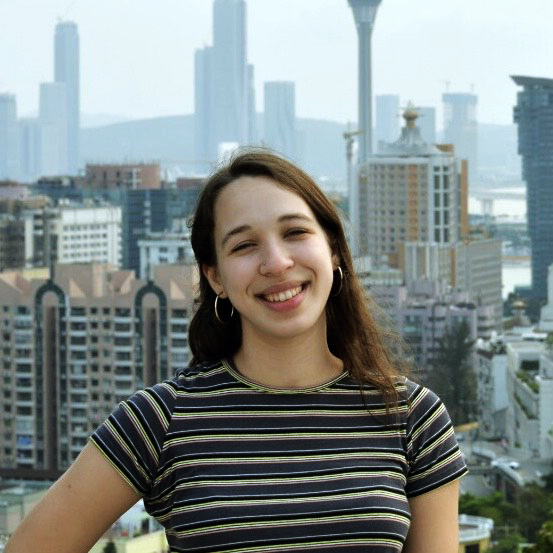 Emma Pred-Sosa smiles in front of a city.