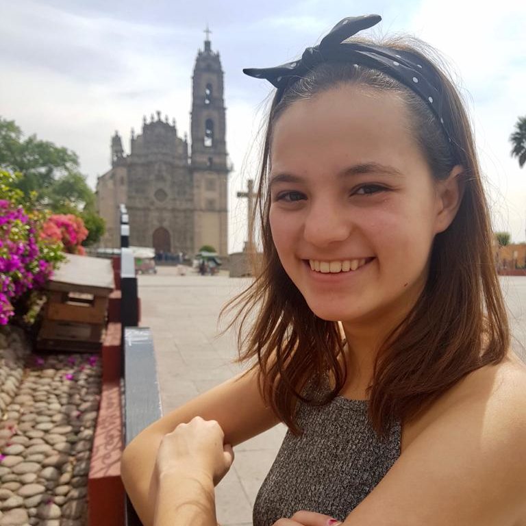 Emma Pred-Sosa smiles in front of a city.